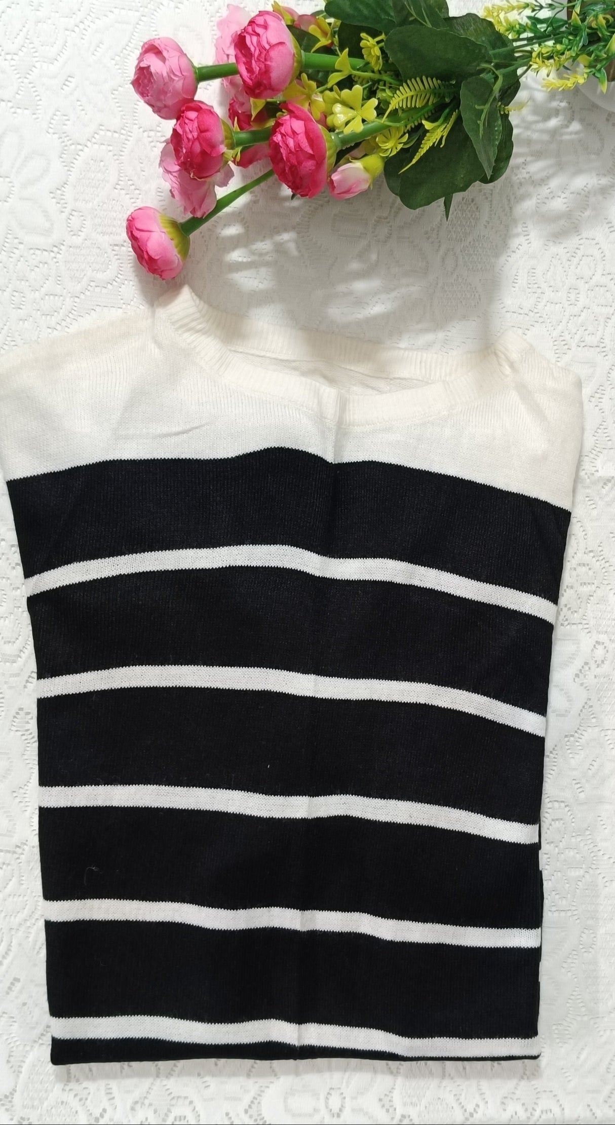 Black and white striped towel with pink flowers and green leaves on a white surface.