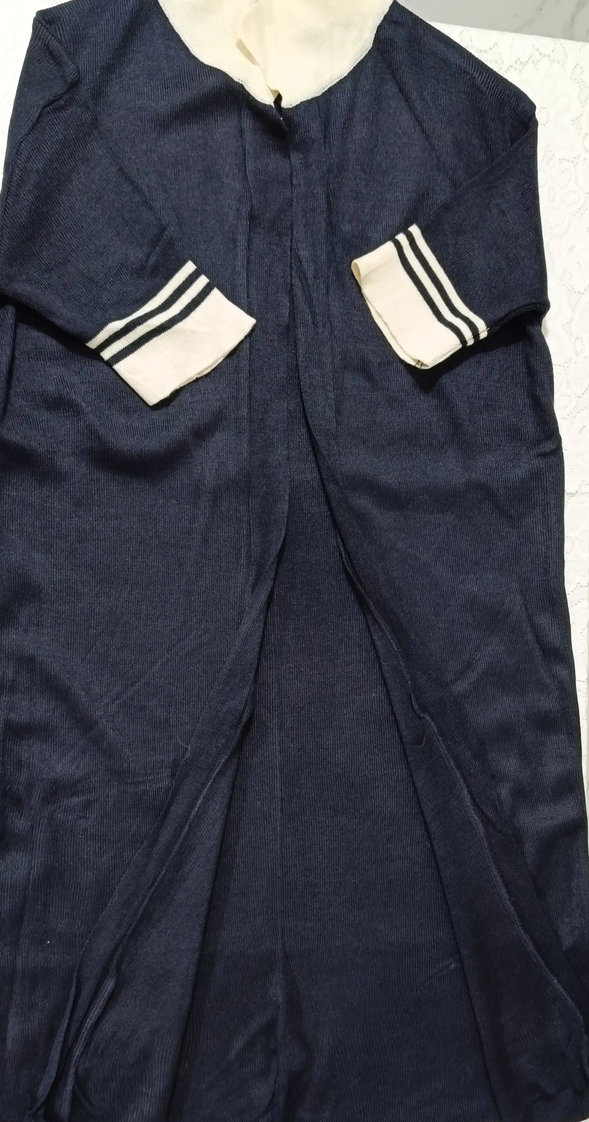 Navy blue garment with white accents on a light gray background