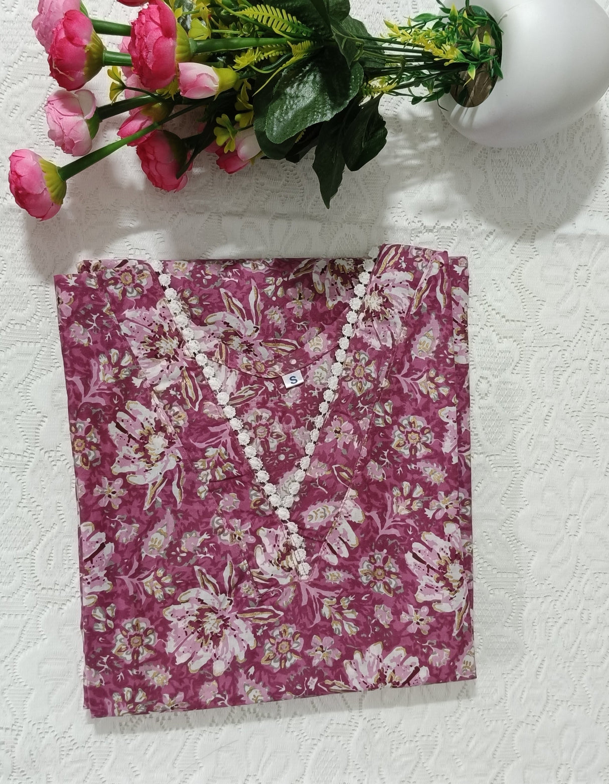 Pink floral notebook on a white surface with pink flowers in front