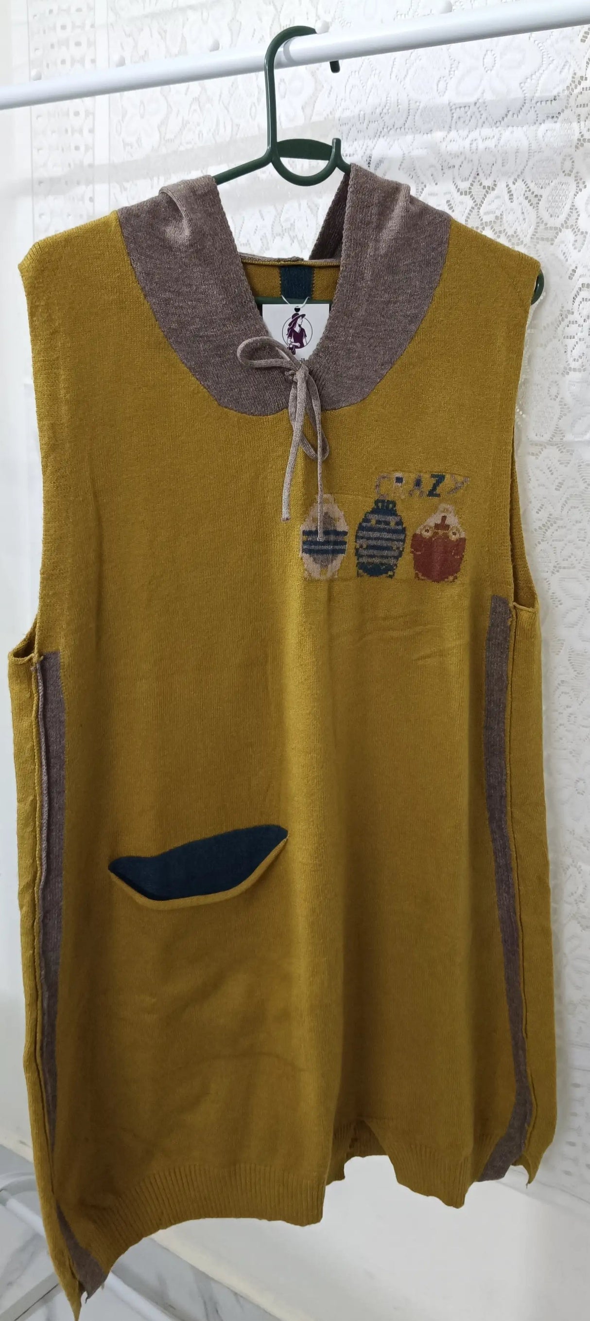 Yellow vest with brown collar and blue pocket on a hanger against a white background