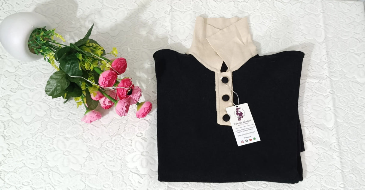 Black shirt with beige collar on a white surface next to pink flowers