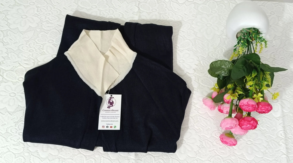 Black and white garment with a tag on a textured surface next to a small potted plant.