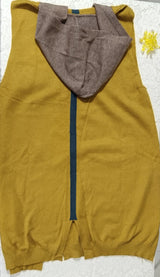 Yellow sleeveless hoodie with brown hood on a white block against a marble background