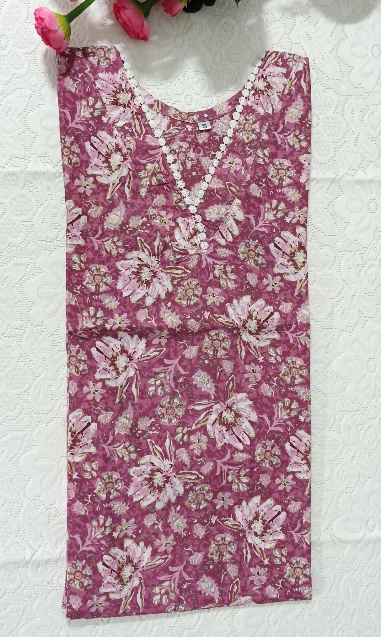 Floral-patterned fabric on a white surface with pink flowers and green leaves.