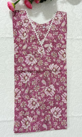 Floral-patterned fabric on a white surface with pink flowers and green leaves.