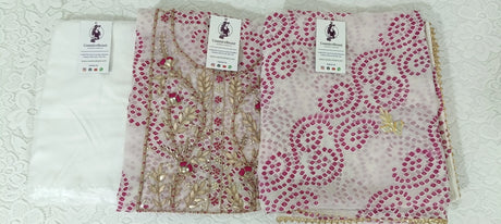 Two pink fabric samples with gold patterns on a textured surface