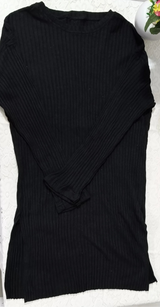 Black sweater on a white surface with pink flowers in the background